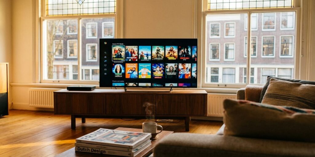 Moderne smart TV met streaming interface op mediameubel in Nederlandse woonkamer met kanaalhuis ramen